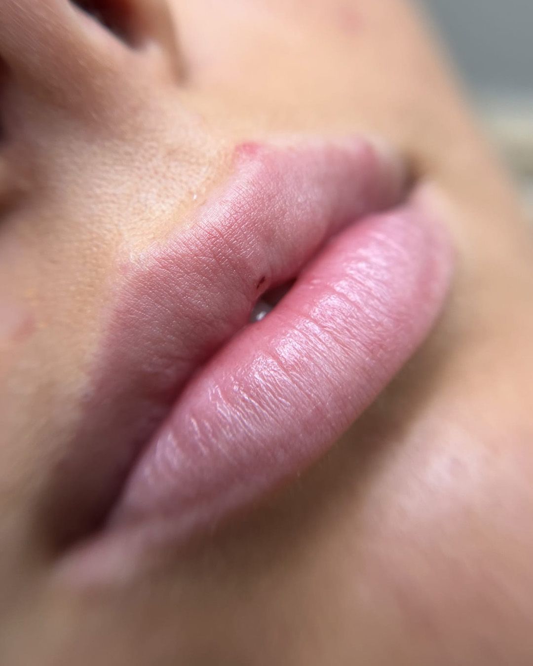 Close-up van volle, lichtroze lippen, lichtjes schuin, met subtiele lijntjes en kleine oneffenheden.