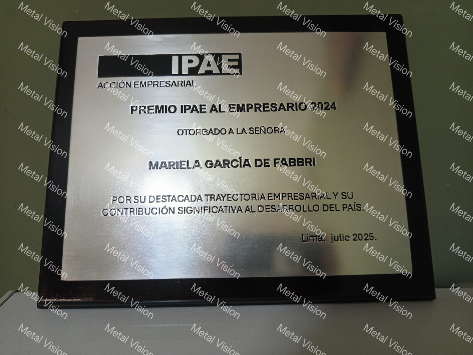Letrero decorativo de metal con texto en relieve que dice “BAIERENTATION PYSTUXE” sobre un fondo gris.
