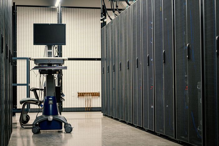 Server room with black server racks and a cart-mounted monitor in the foreground