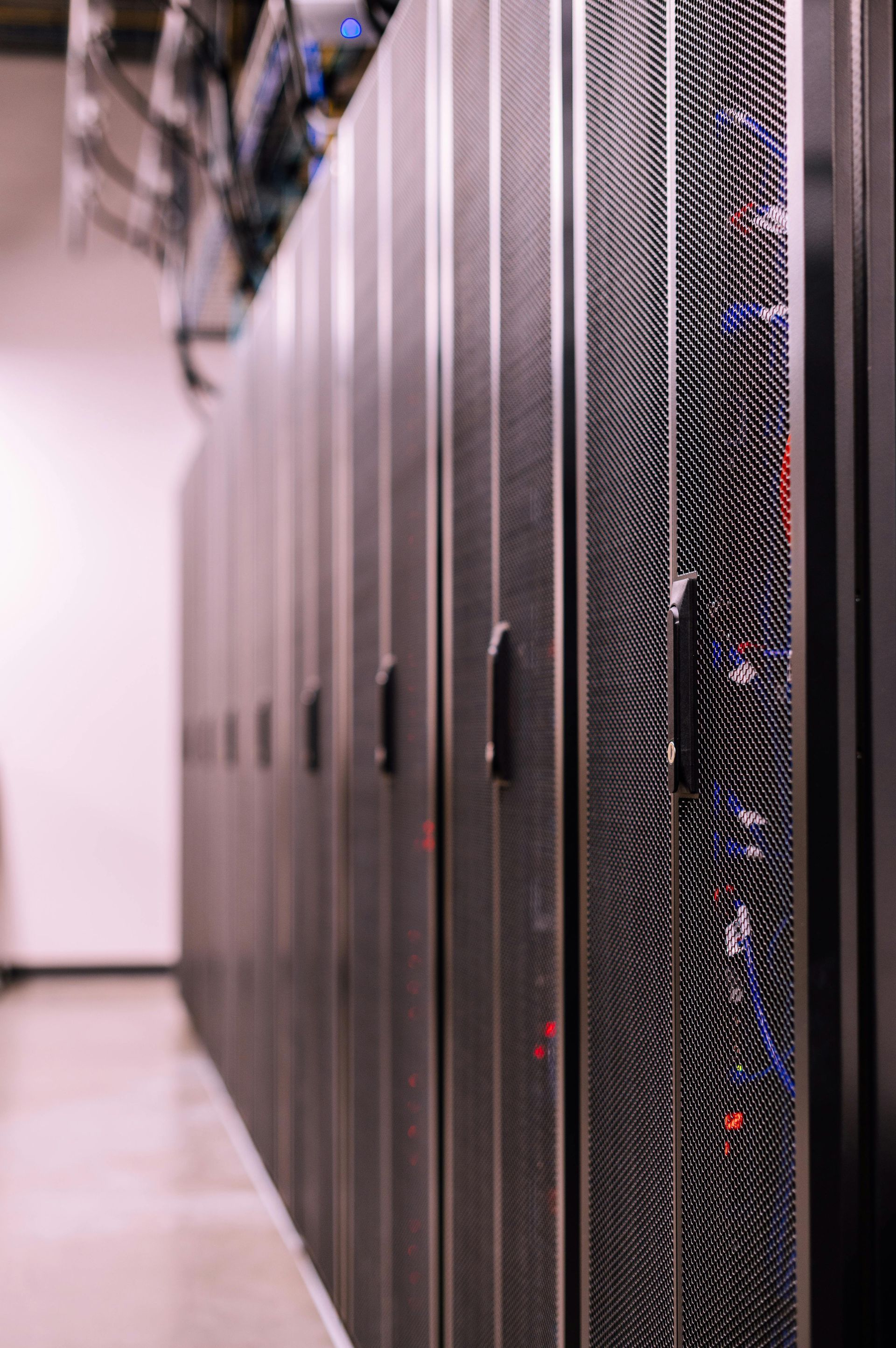 Row of black server racks in a data center corridor with blinking status lights