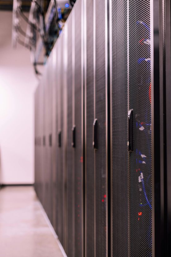 Row of black server racks in a data center corridor with blinking status lights