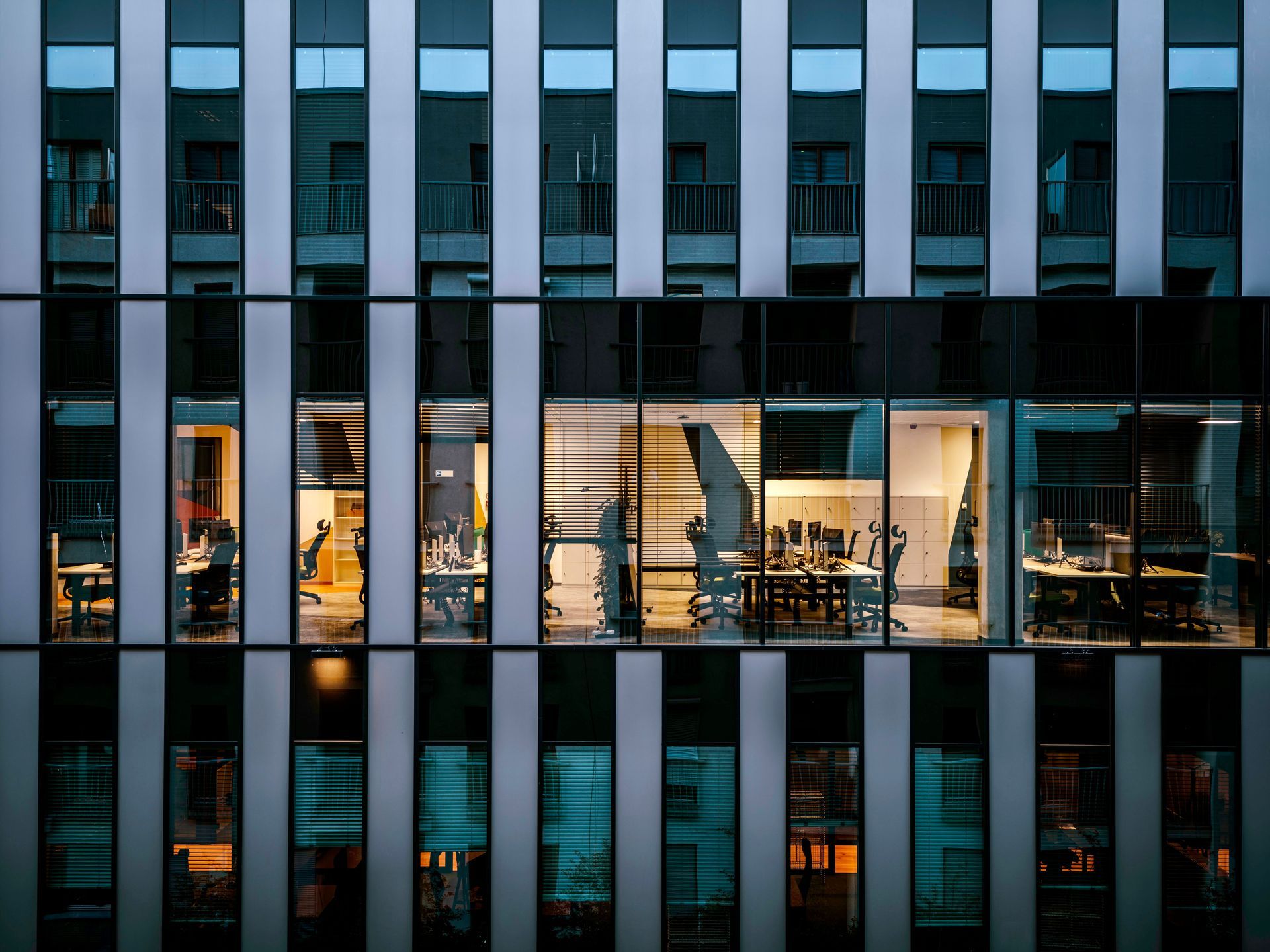 Photograph of a modern office building facade featuring vertical black and white panels with a central row of large windows