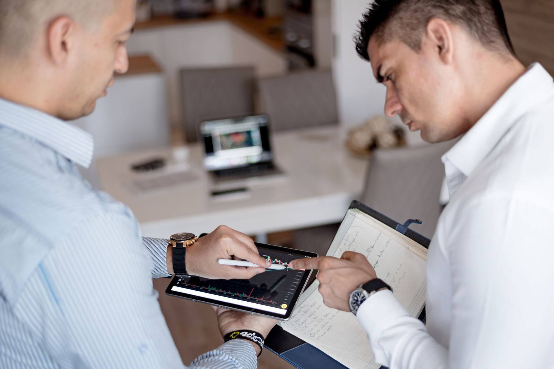 Two professionals reviewing financial data and market charts together on a digital tablet.