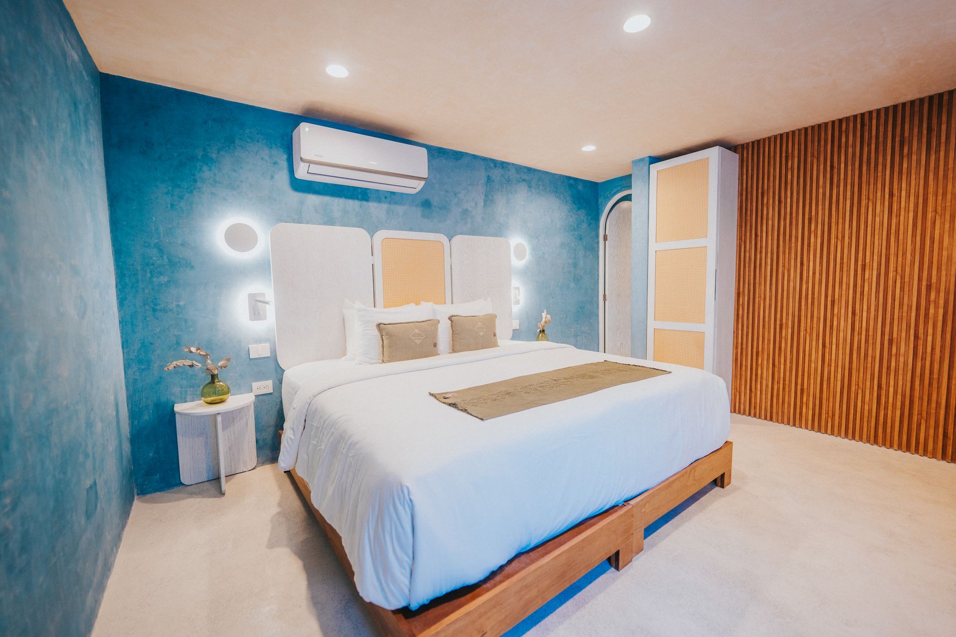 Dormitorio con pared azul, ropa de cama blanca y detalles de madera.