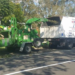 A Green Tree Chipper is Parked Next to a White Truck — All Australian Tree & Palm Services In Mount Coolum, QLD