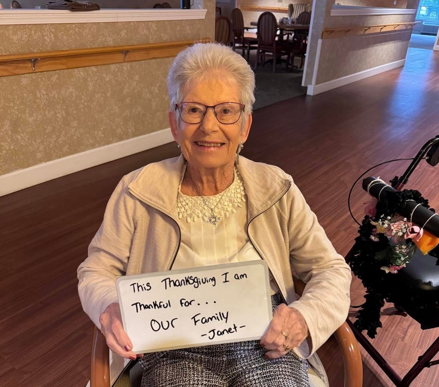 A woman smiling and holding a sign that reads,