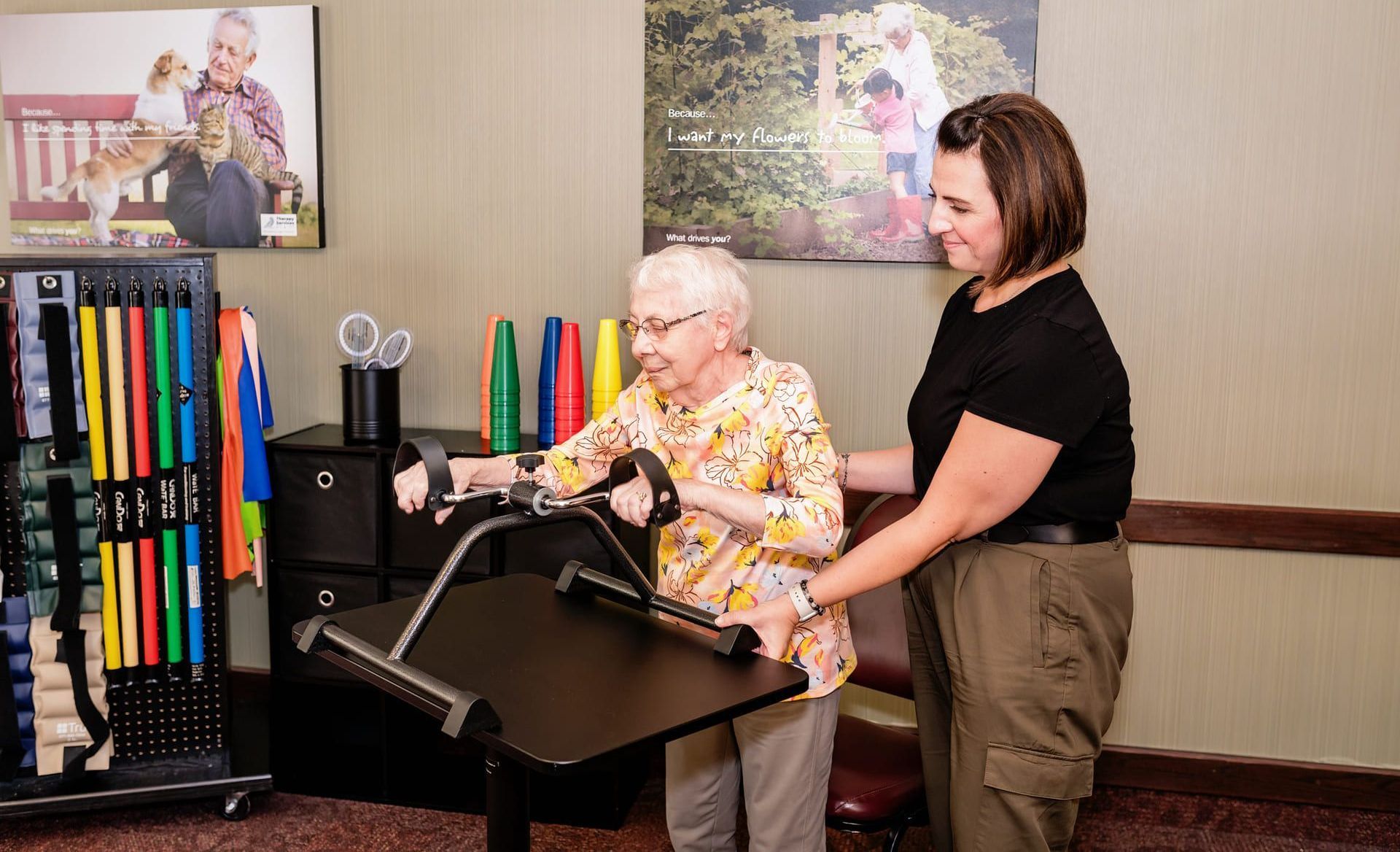 A woman is helping an elderly woman do exercises on a machine.
