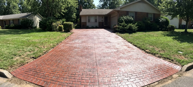 A durable stamped concrete driveway with a realistic brick pattern and red coloring.
