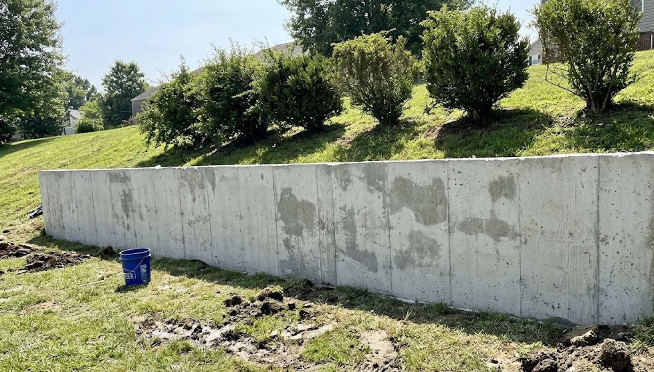 Smooth concrete retaining wall in a Columbia MD backyard holding back a grassy slope.