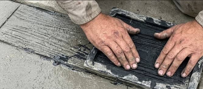 Close up of the concrete stamping installation process creating a faux wood plank texture.