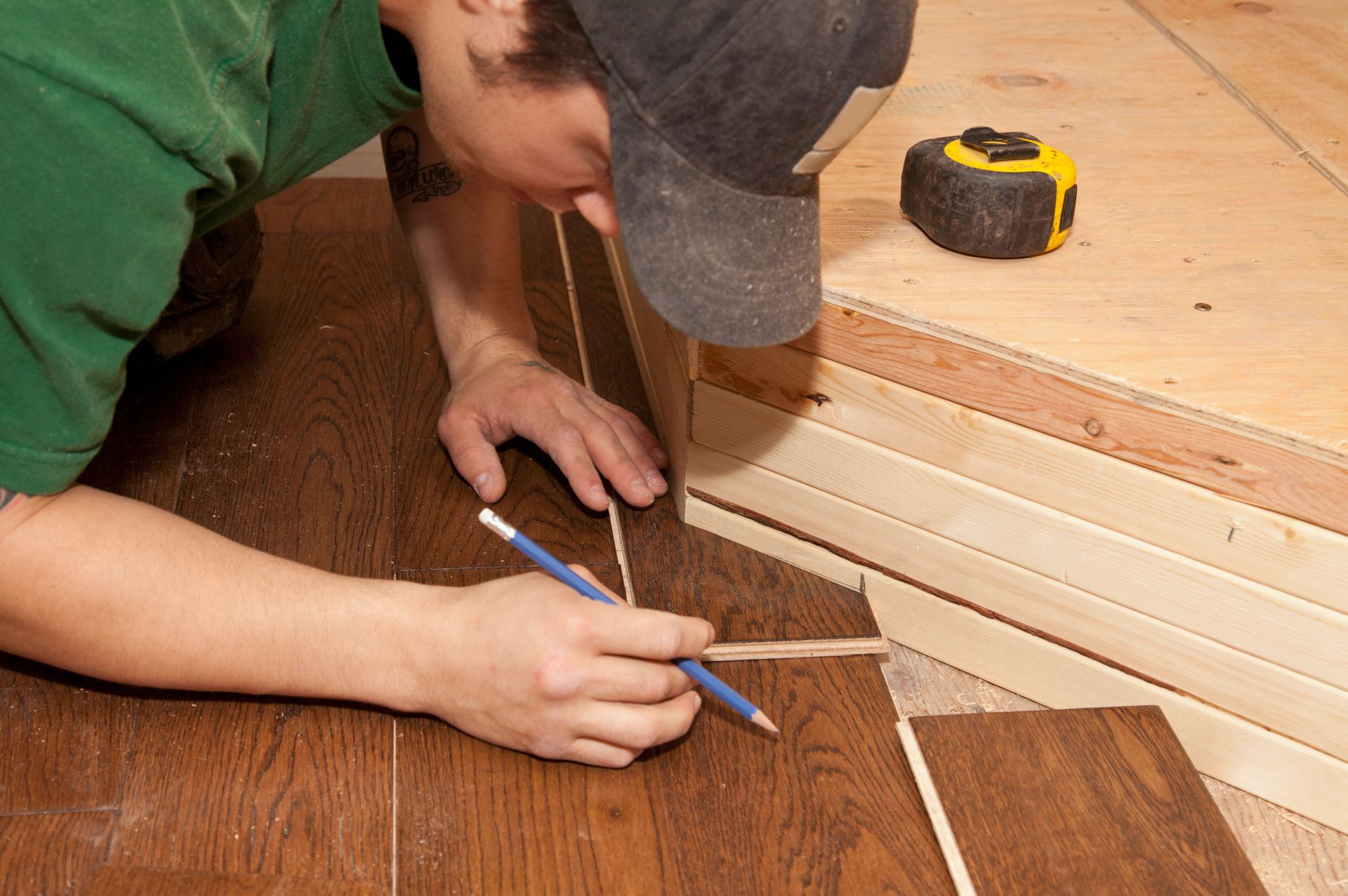 A man is measuring a piece of wood with a pencil.