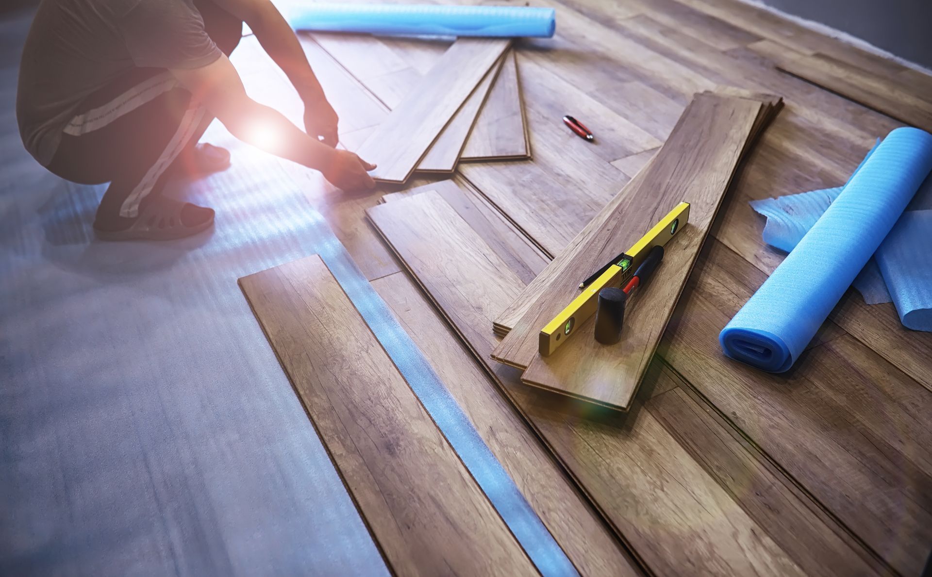 A man is installing a wooden floor in a room.