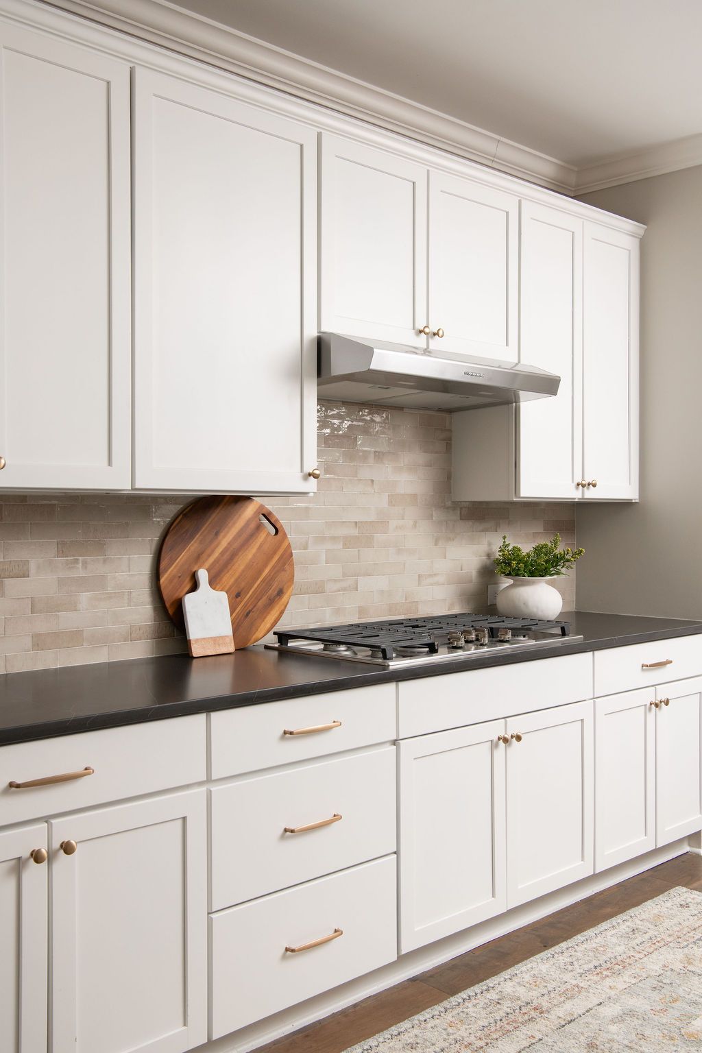 A kitchen with white cabinets , black counter tops , and a stove top oven.