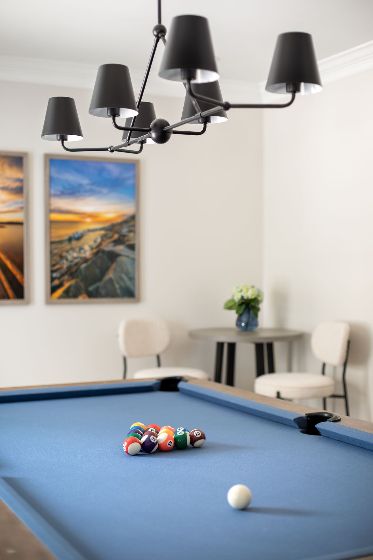 A pool table in a game room with a chandelier hanging from the ceiling.