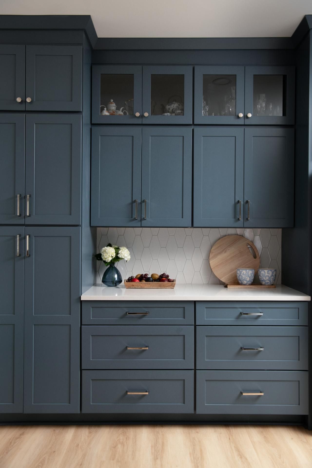 Blue kitchen cabinets with white countertop, wood cutting board, and fruit, in a bright room | Matthews, NC | An Inspiring Home