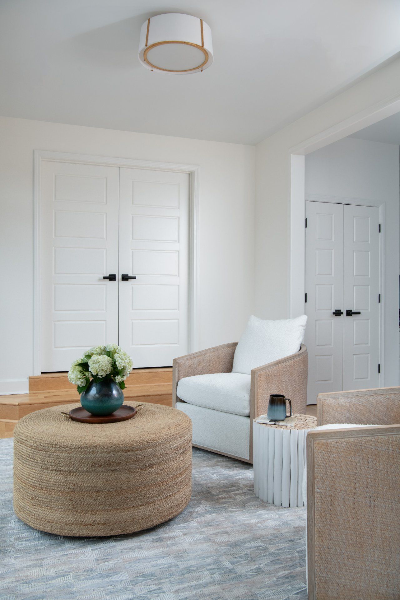 Living room with white walls, doors, and furniture. A jute ottoman, armchair, and side table | Charlotte, NC | An Inspiring Home