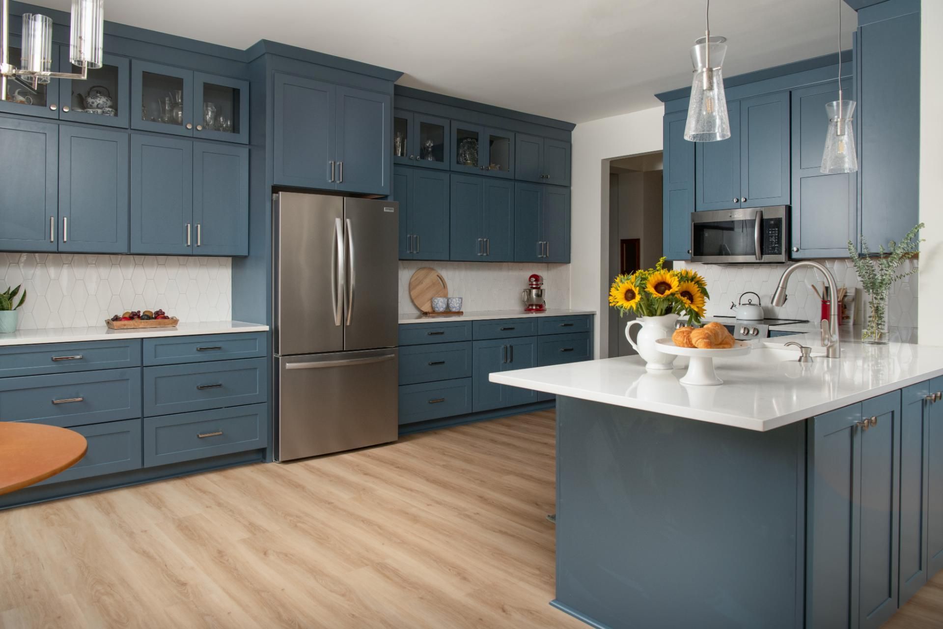 Blue kitchen with island, stainless steel refrigerator, and sunflowers on the countertop | Matthews, NC | An Inspiring Home