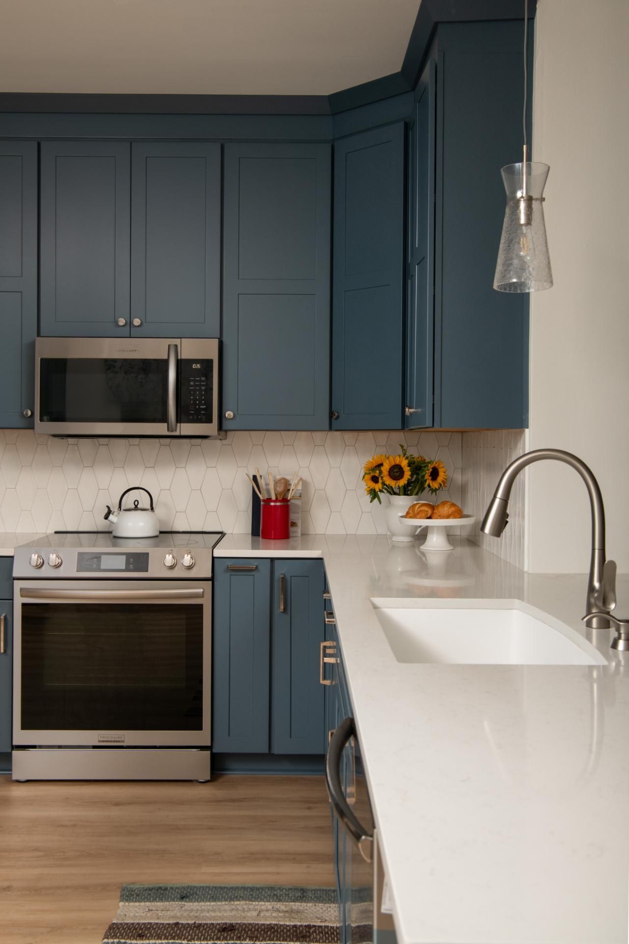 Blue kitchen with white countertop, stainless steel appliances, and small floral arrangement | Matthews, NC | An Inspiring Home