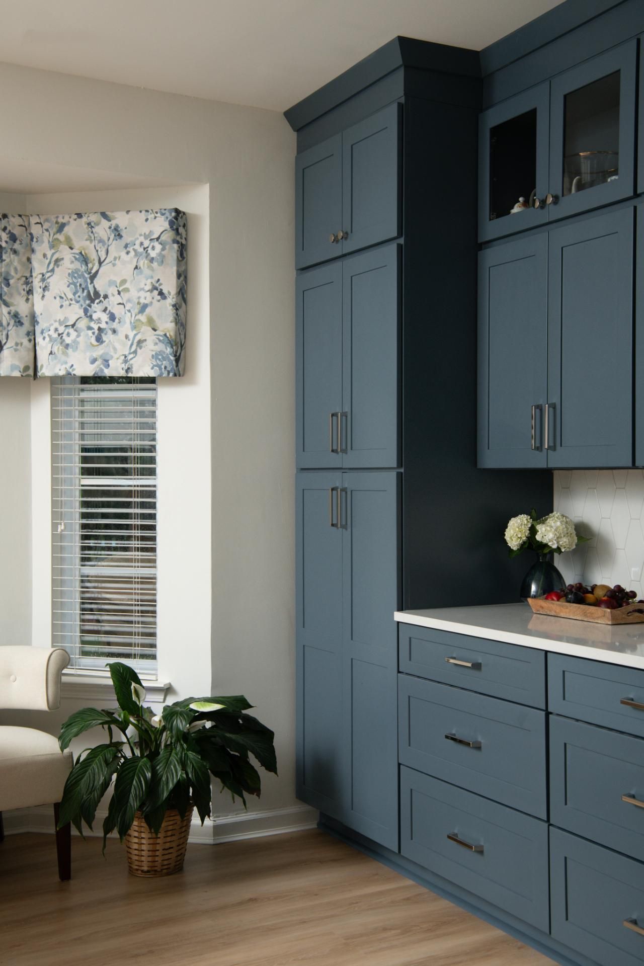 Blue kitchen cabinets with a white countertop and a window with a floral valance | Matthews, NC | An Inspiring Home