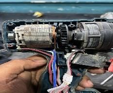 Apertura del actuador de la cerradura de la puerta del coche con el cableado expuesto y una mano sujetando el conector.