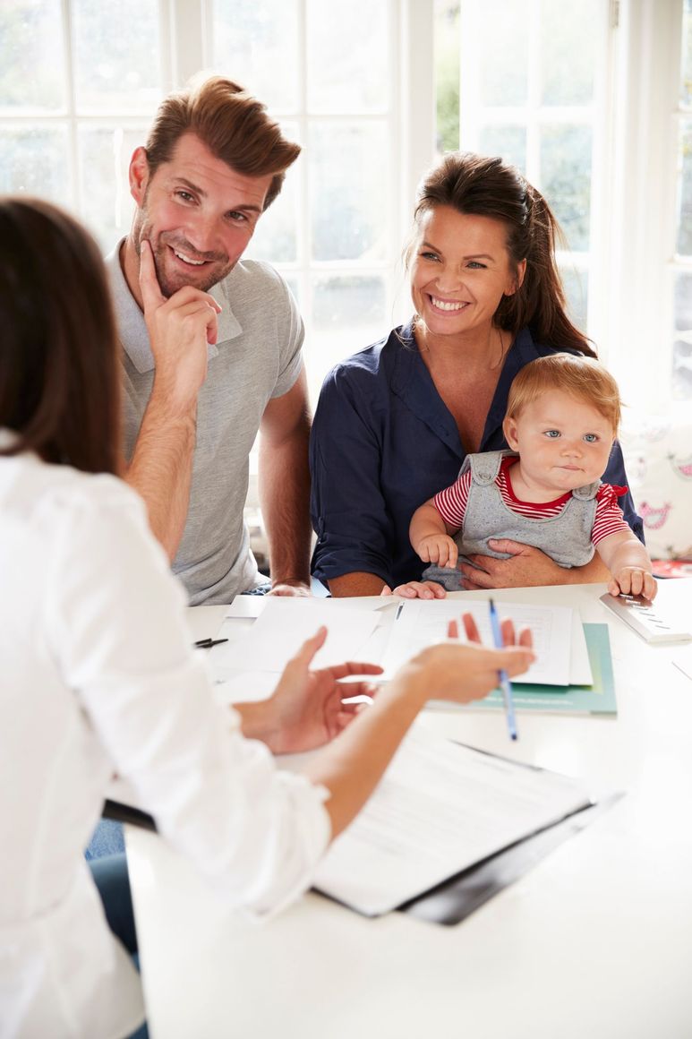 Family speaking with a counselor at a bright table, with a baby sitting on one parent’s lap.