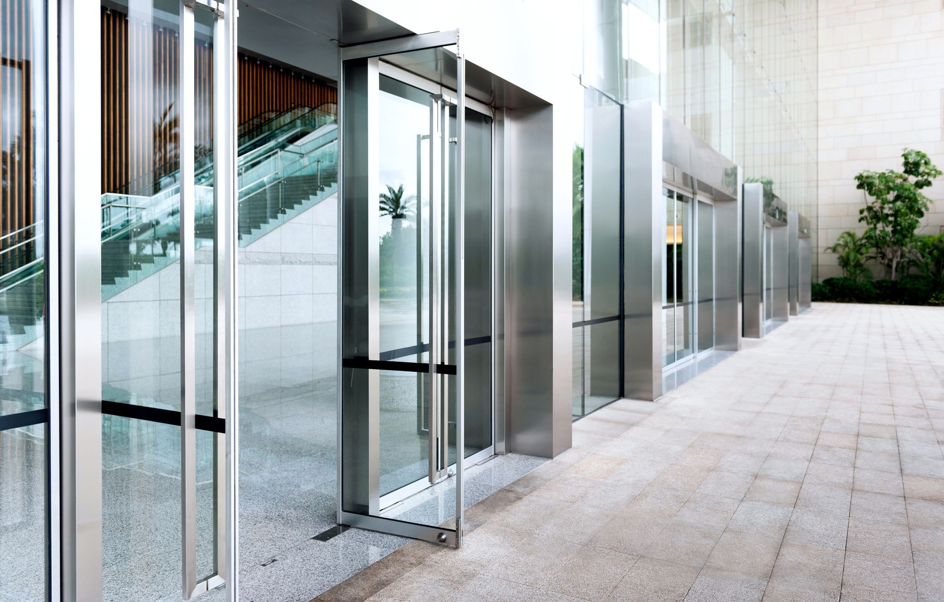 Portes d'entrée vitrées donnant sur une passerelle moderne avec un escalier à l'intérieur du hall