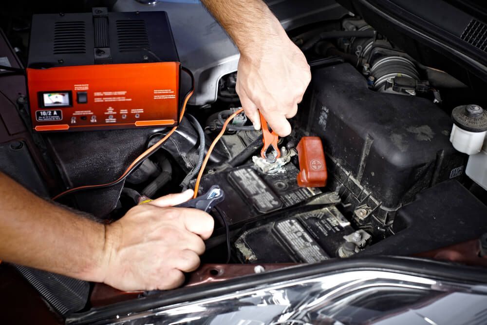 A Person Is Charging A Car Battery With A Charger — Coast 2 Coast Batteries in Kincumber, NSW