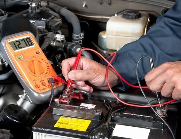 A Man Is Using A Multimeter To Test A Car Battery — Coast 2 Coast Batteries in West Gosford, NSW