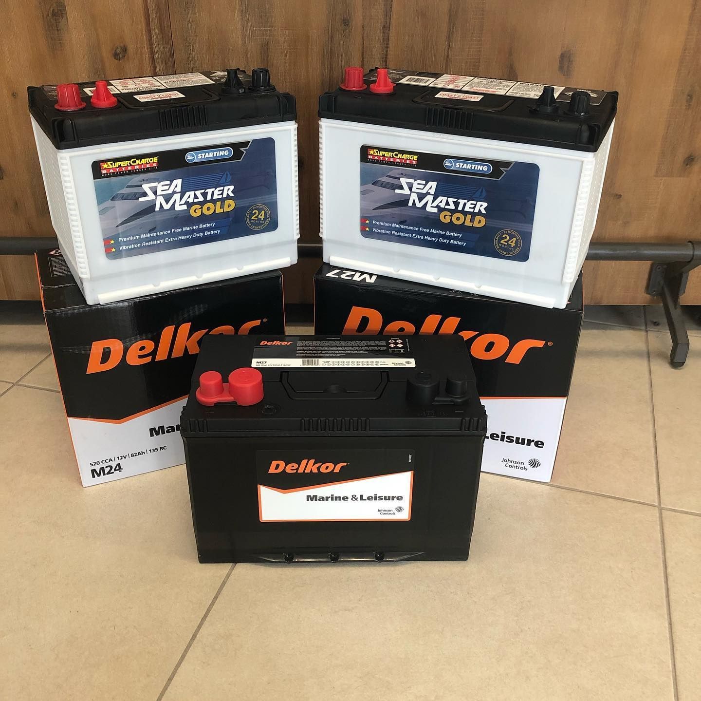 Three Delkor Batteries Are Sitting On Top Of Each Other On A Tiled Floor — Coast 2 Coast Batteries in West Gosford, NSW
