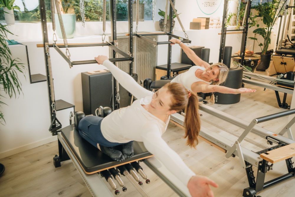 Two women are doing exercises on a pilates reformer in studio