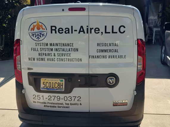 White service van for Real-Aire, LLC with HVAC and refrigeration company contact info on the back