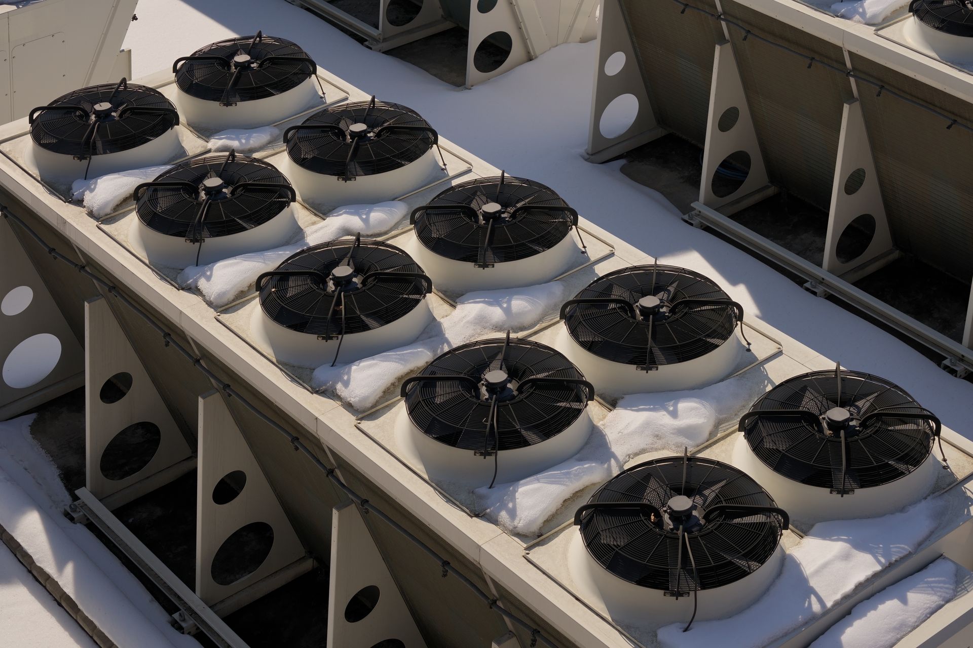 Rows of black cooling fans mounted on a rooftop HVAC unit under daylight