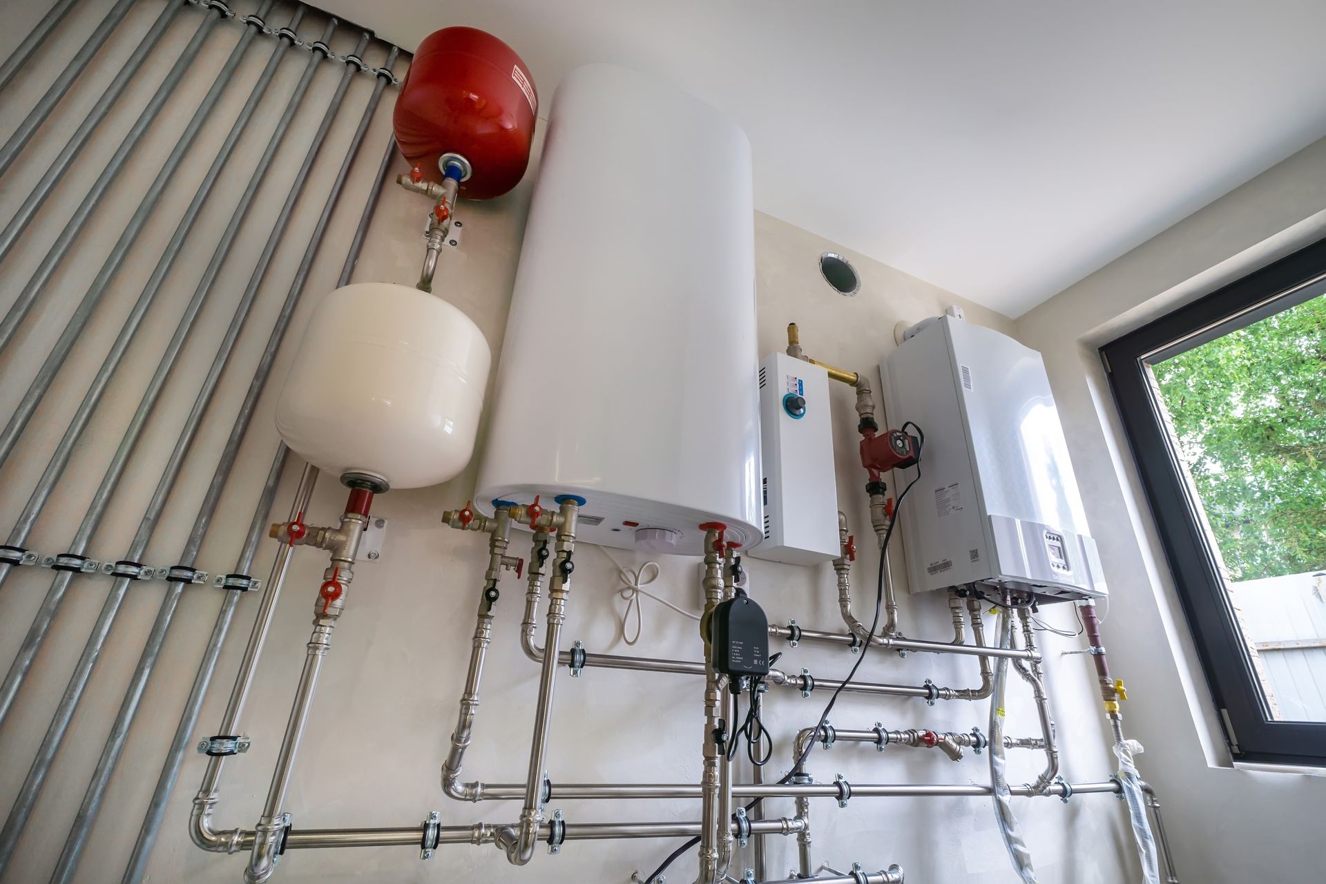 Wall-mounted boiler system with pipes, tanks, and gauges in a utility room