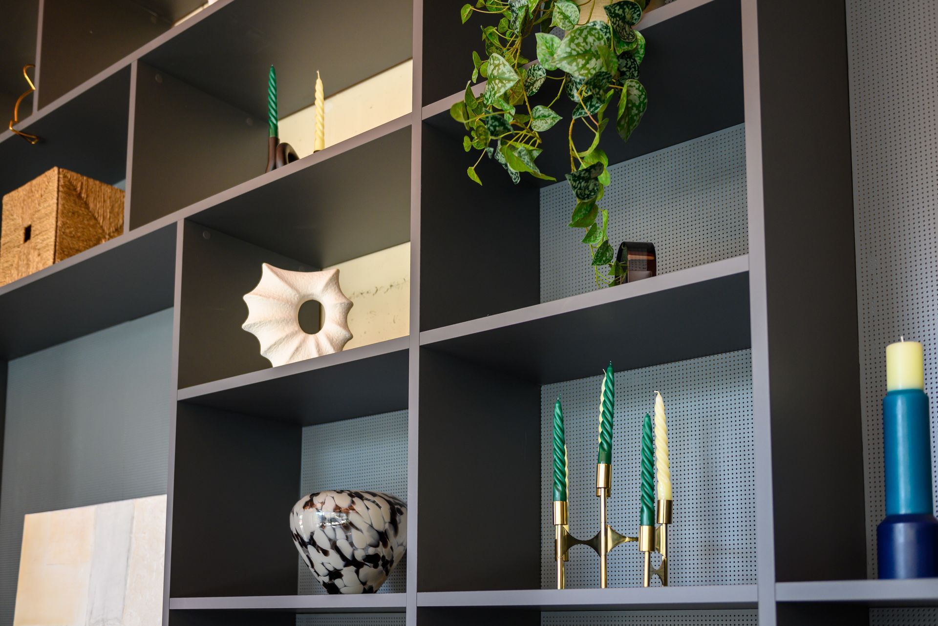 Decorative shelving with plants, candles, vase, and wall art in a modern room