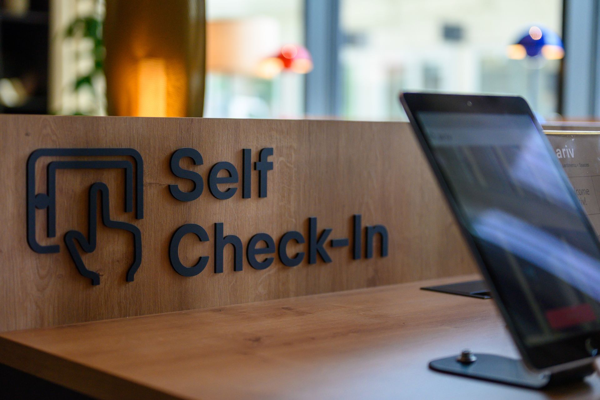 Wooden self check-in desk with a touchscreen kiosk in a modern lobby