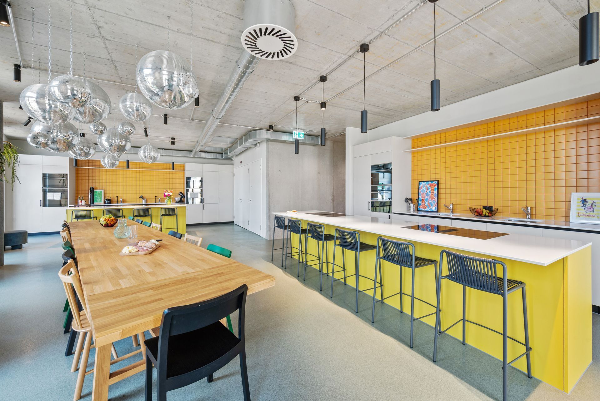 Modern kitchen with wooden dining table, yellow breakfast bar, and hanging pendant lights