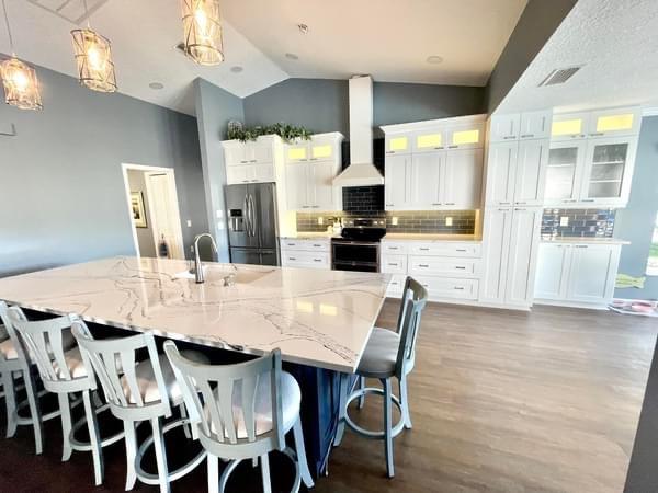The after photo shows a sunny, bright white kitchen with ample storage and light.
