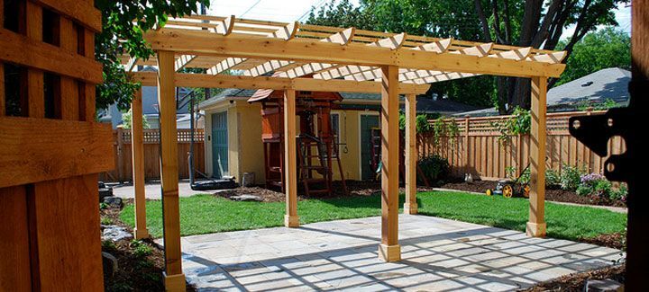 A wooden pergola is sitting in the backyard of a house.
