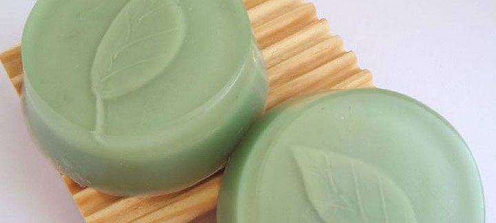Two green soaps are sitting on a wooden soap dish.