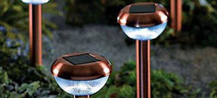 A group of copper solar lights are sitting on top of each other in a garden.
