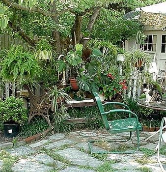 A green chair is sitting in the middle of a garden surrounded by plants.