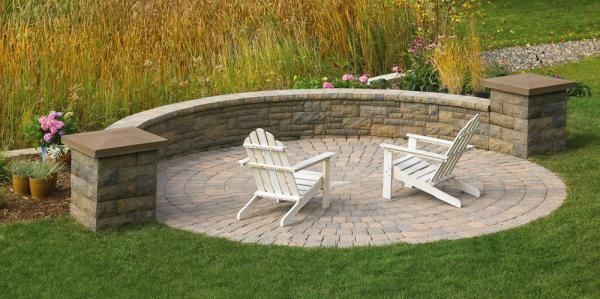 Two white chairs are sitting on a brick patio next to a stone wall.