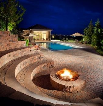 A fire pit in the middle of a patio next to a pool