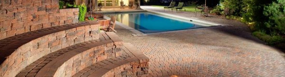 A swimming pool is surrounded by a brick wall and steps leading to it.