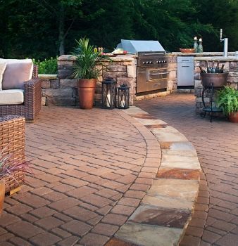 A brick patio with a couch and a grill