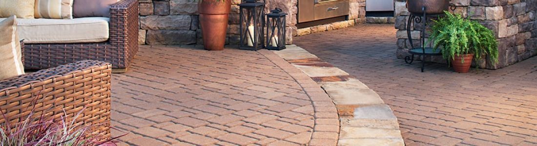 A patio with a couch , chairs , lanterns and potted plants.