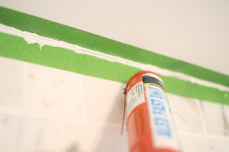 A can of silicone sealant is being applied to a wall.