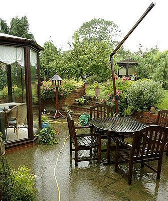 A patio with a table and chairs in the rain.