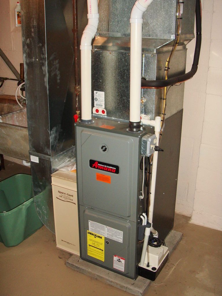 An air conditioner is sitting in a basement next to a box