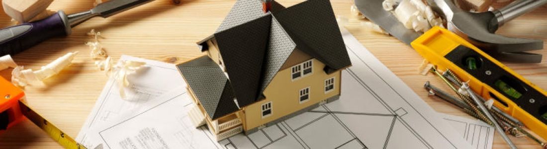 A model house is sitting on top of a blueprint on a wooden table.